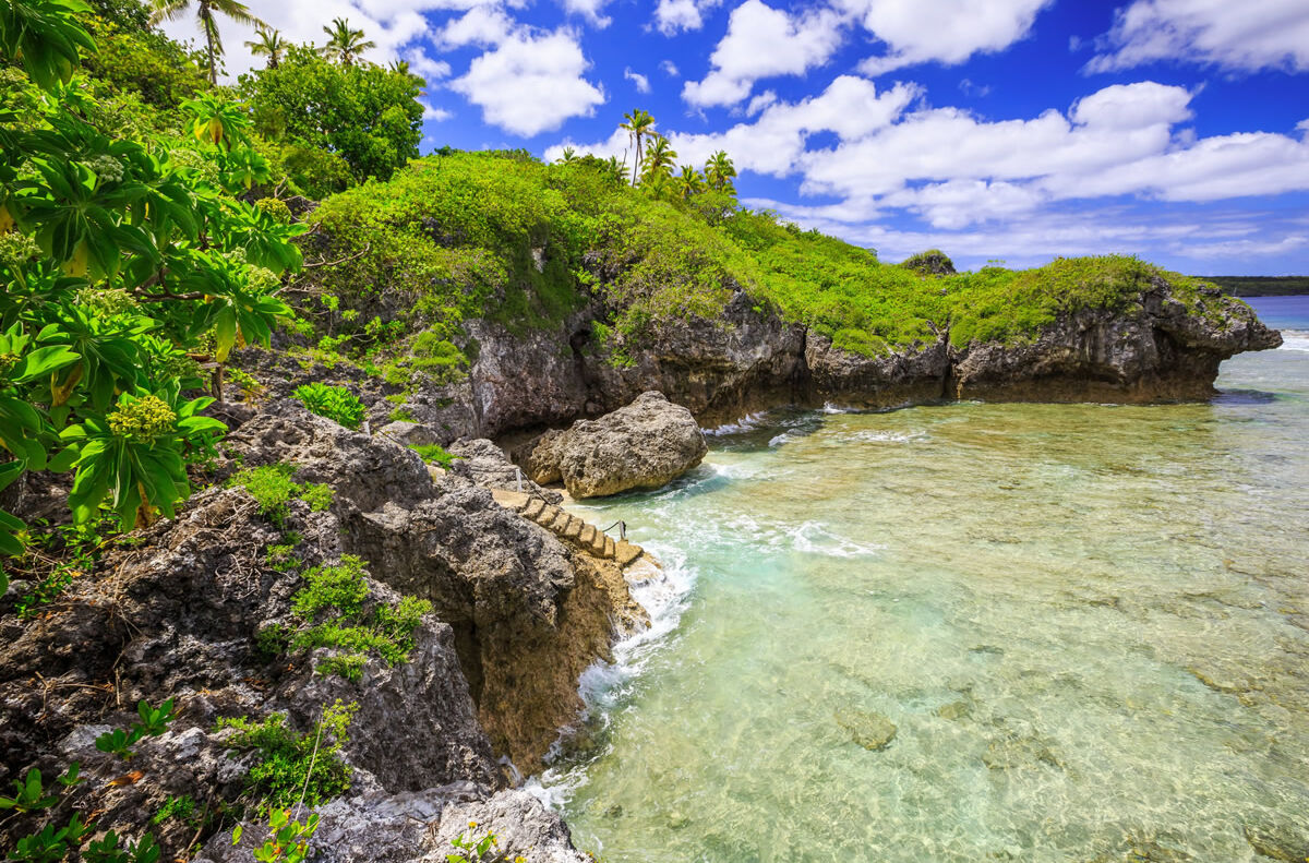 Meer und prächtig grüner Fauna am Strand von Niue